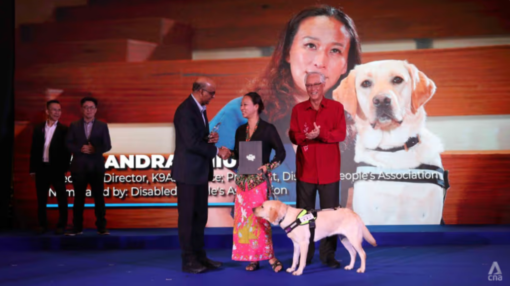 Photo shows Ms Cassandra Chiu with her guide dog, receiving the Goh Chok Tong Enable Awards 2024.