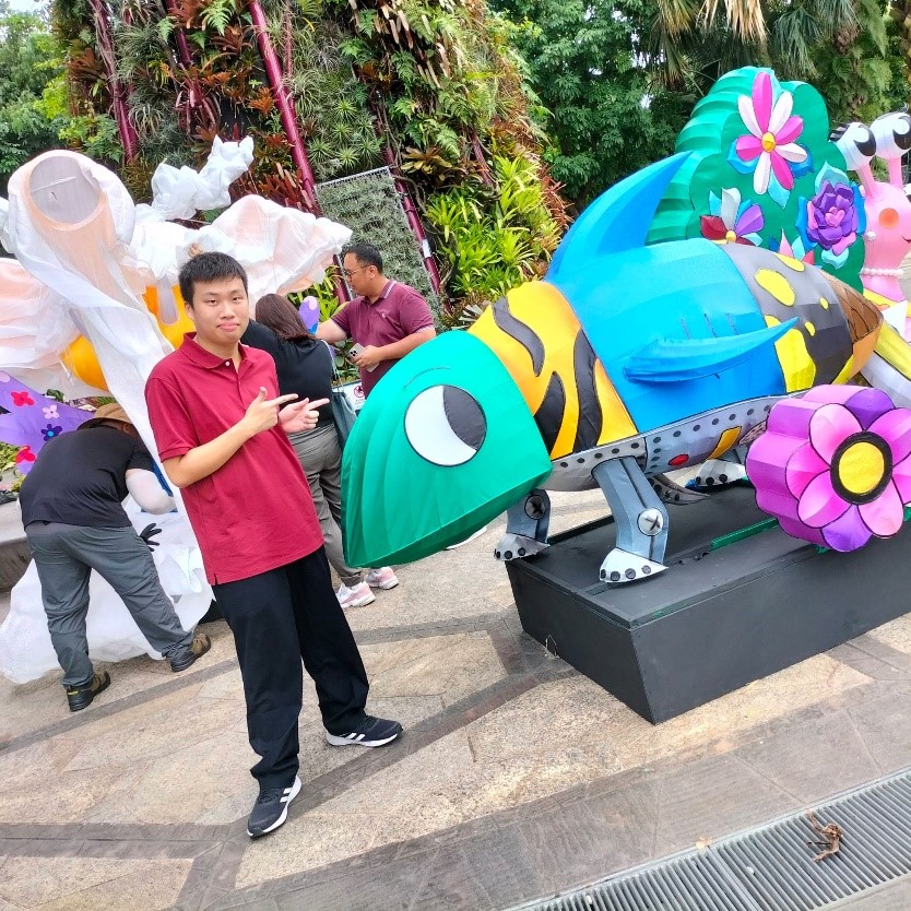 Image shows a boy posing beside a chameleon display.